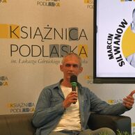 Marcin Silwanow siedzi na kanapie w Galerii Parter.