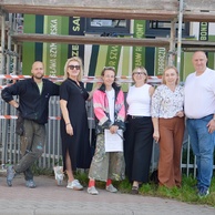 Komisja odbiorowa oraz wykonawcy stoją przed muralem „Książki do nieba” podczas jego odbioru.